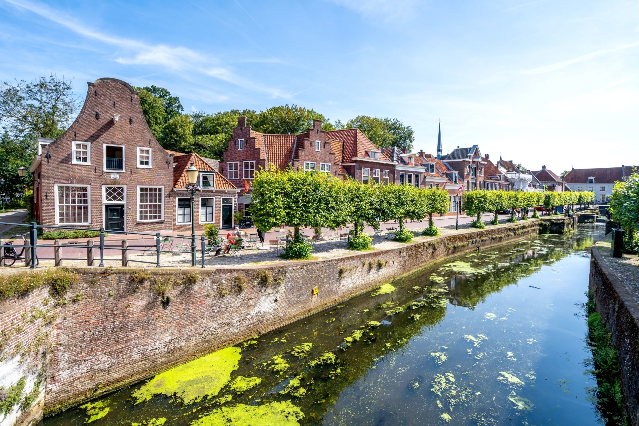 Een oever in Amersfoort, op de kade staan historische huizen. De foto is vanaf het water genomen.